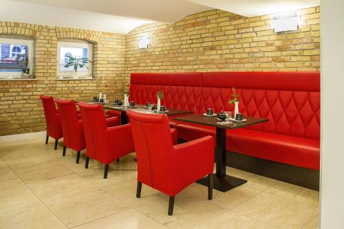 a restaurant with red booths and tables and red chairs at Haus Hotel & Pension Villa Laluna in Blankenburg
