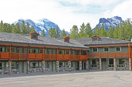 a large building with a deck with mountains in the background at Mountaineer Lodge in Lake Louise