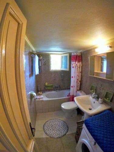 a bathroom with a tub and a toilet and a sink at Agnanti house in Symi