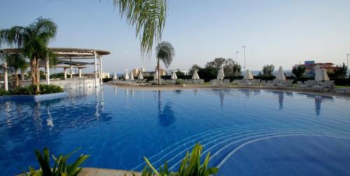 a large swimming pool with chairs and umbrellas at Sunrise Oasis Hotel & Waterpark in Protaras