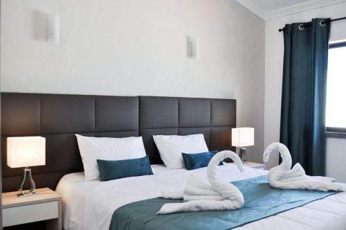 2 asciugamani cigni su un letto in una camera da letto di Casa Areias Boutique Apartments ad Albufeira