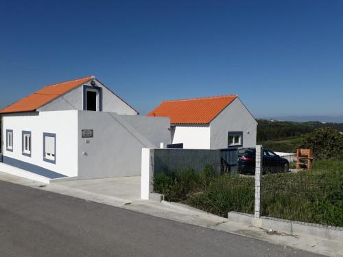 une maison blanche avec un toit orange à côté d'une rue dans l'établissement Villa Ricardo, à Alcobaça