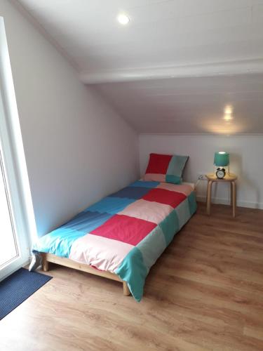a bedroom with a bed with colorful sheets and a window at Villa Ricardo in Alcobaça