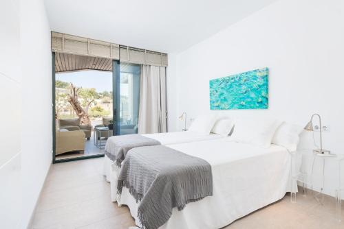a white bedroom with two beds and a balcony at Mirador Blue D - Cala Sant Vicenç in Cala de Sant Vicenc
