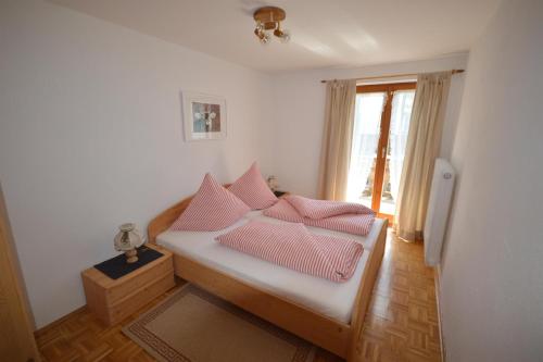 Habitación con cama con almohadas rosas. en Haus Alpenblick, en Oberjoch