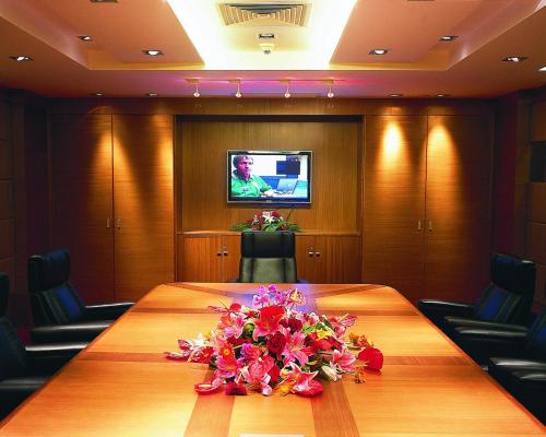 a conference room with a large wooden table with flowers on it at Furama Hotel Dalian in Dalian