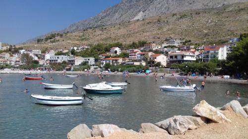 a group of people on a beach with boats in the water at Summerhouse Duće Omiš in Duće