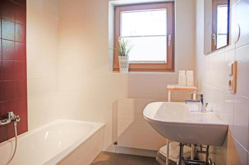 een witte badkamer met een bad en een wastafel bij Appartement Herzogbauer in Saalfelden am Steinernen Meer