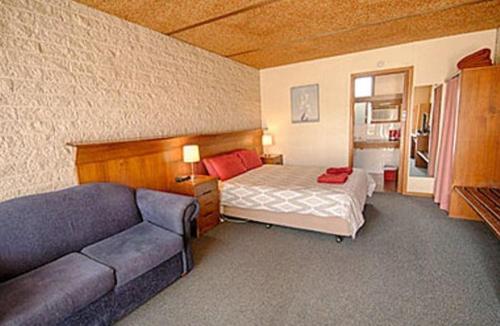 ein Schlafzimmer mit einem Bett und einem Sofa in der Unterkunft Darlot Motor Inn in Horsham