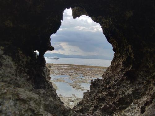 a view of the ocean through a hole in a rock at Ancelle Cristo Re in Moalboal