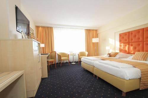 a hotel room with two beds and a flat screen tv at Best Western Plus Hotel Steinsgarten in Gießen