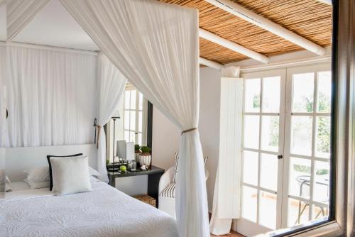 a white bedroom with a bed and a window at Quinta da Lua in Tavira