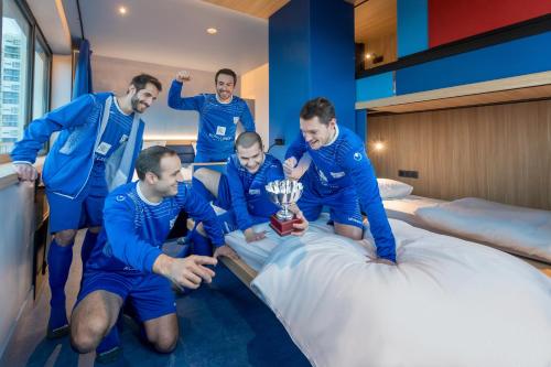 a group of men standing around a bed with a trophy at YOOMA Urban Lodge Tour Eiffel in Paris