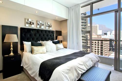 um quarto com uma cama grande e uma janela grande em Luxury Apartments at the Icon, Walking distance to CTICC in Cape Town em Cidade do Cabo