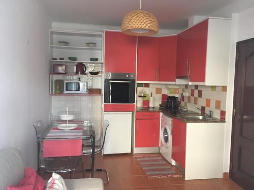 ヴィラ・ノヴァ・デ・ミルフォンテスにあるStudio do Brejo - de 2 a 3 pessoasの赤いキャビネットとテーブル付きのキッチンが備わります。
