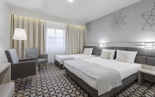 a hotel room with two beds and a chair at Kocierz Resort in Targanice