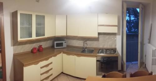 a kitchen with white cabinets and a sink and a microwave at Casa della Nonna 2 in Gargnano