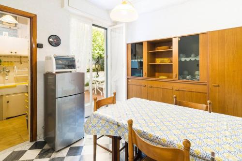 a kitchen and dining room with a table and a refrigerator at Grazioso appartamentino a due passi dalla pista ciclabile con Giardino e Garage in Sanremo
