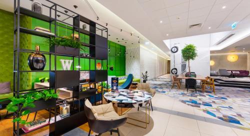 a lobby with a green wall and a table and chairs at Mercure Warszawa Grand in Warsaw