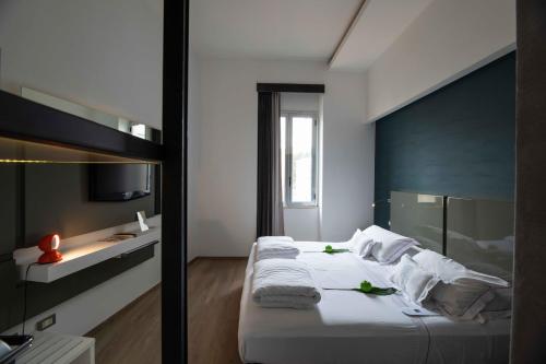 a bedroom with a bed with white sheets and a window at UNA HOTELS One Siracusa in Siracusa