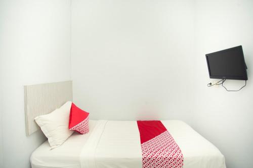 a bedroom with a bed with a tv on the wall at Hotel O Lapan Lapan in Banjarmasin