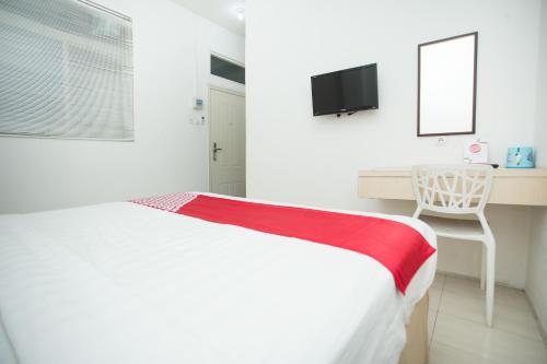 a bedroom with a bed and a desk and a television at Hotel O Lapan Lapan in Banjarmasin