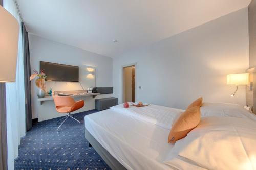 a hotel room with a bed and a desk at Best Western Plus Hotel Steinsgarten in Gießen