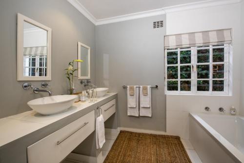 een witte badkamer met 2 wastafels, een bad en een bad tubermott bij In Abundance Guest House in Montagu