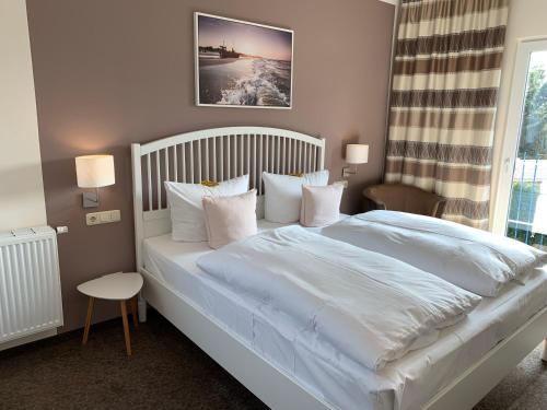 a bedroom with a large bed with white sheets and pillows at Pension Richter in Ostseebad Nienhagen