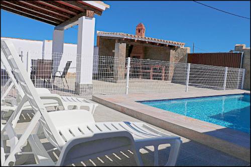 - un groupe de chaises assises à côté de la piscine dans l'établissement Chalet Ermita, à Conil de la Frontera