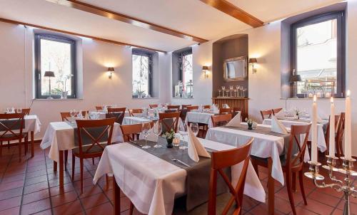 ein Restaurant mit weißen Tischen, Stühlen und Fenstern in der Unterkunft Hotel Eisenbahn in Karlstadt