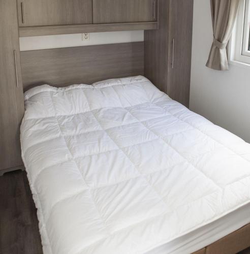 a large white bed in a small room at 4 pers. Veluwelounge in Voorthuizen