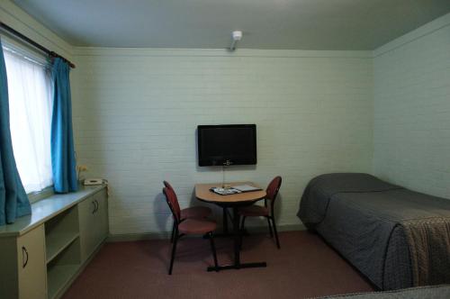 a bedroom with a table and a bed and a television at City Waters in Perth