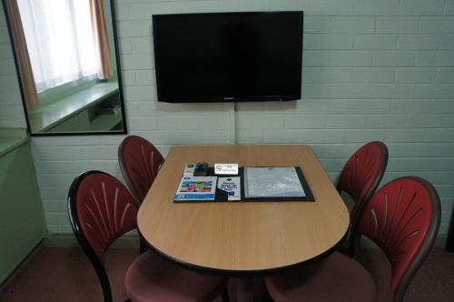 a room with a table with chairs and a television at City Waters in Perth