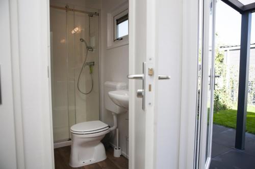 La salle de bains blanche est pourvue d'une douche et de toilettes. dans l'établissement 6 pers. Veluwelodge XL met Sauna, à Voorthuizen