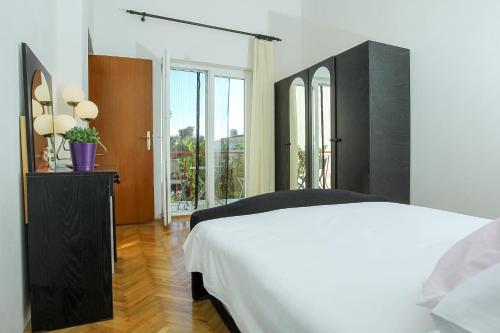 a bedroom with a white bed and a large window at Villa Palma in Petrcane