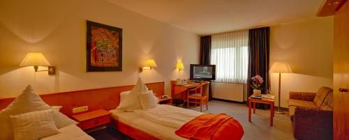 a hotel room with two beds and a desk at Trip Inn Hotel Zum Riesen Hanau in Hanau am Main