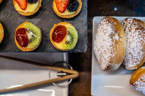 a bunch of pastries on a tray with fruit on them at UNA HOTELS One Siracusa in Siracusa