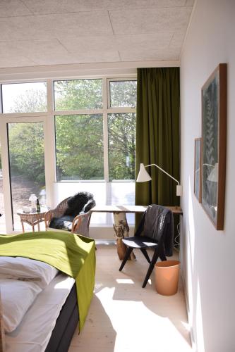 a bedroom with a bed and a desk and windows at Vilcon Hotel & Konferencegaard in Slagelse