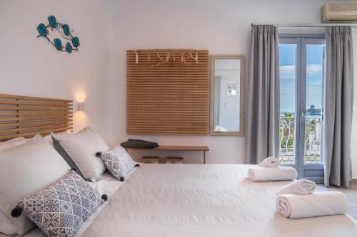 1 dormitorio con 1 cama blanca grande y balcón en Andros Blue, en Ándros