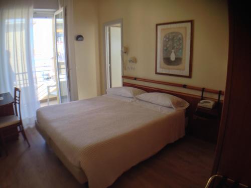 a bedroom with a large white bed and a balcony at Hotel Houston in Rimini