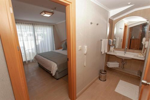 a bedroom with a bed and a bathroom with a sink at Hotel Aqua in Marmaris