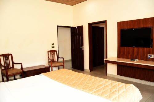 a bedroom with a bed and a flat screen tv at Mastiff Villa Camellia by OTHPL in Pālampur