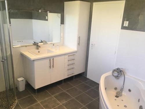 a bathroom with a tub and a sink and a tub at La Maison des Brandes in Eynesse