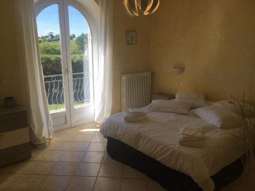 a bedroom with a bed and a large window at La Maison des Brandes in Eynesse