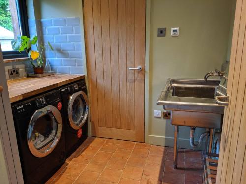 a kitchen with a washing machine and a sink at Helford Cottage in Gweek