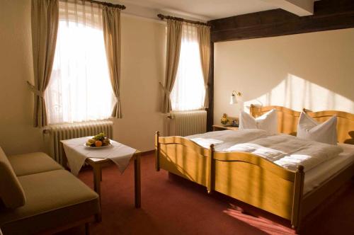een slaapkamer met een bed, een stoel en ramen bij Goldener Hirsch in Burgthann