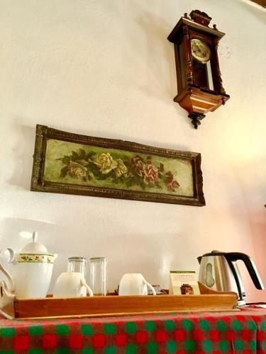 a clock on a wall next to a table with a table sidx sidx at Count Kálnoky's Transylvanian Guesthouses in Micloşoara