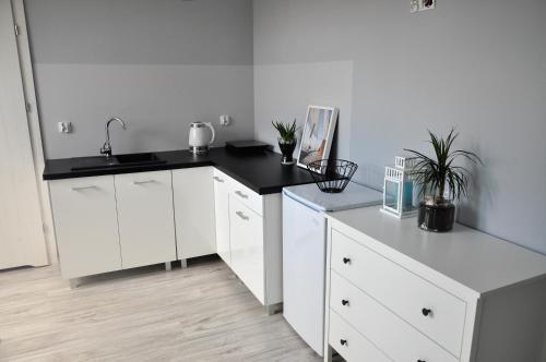 a kitchen with white cabinets and a black counter top at Apartamenty Szotland in Władysławowo