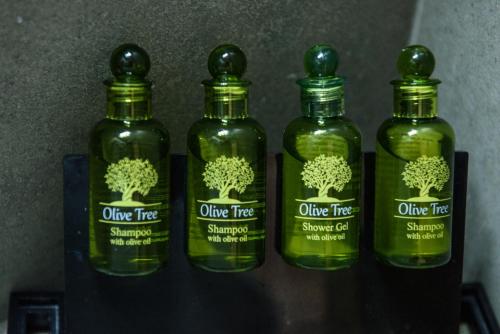 three bottles of olive tree shampoo on a shelf at Paloma Luxury Studios in Panormos Kalymnos